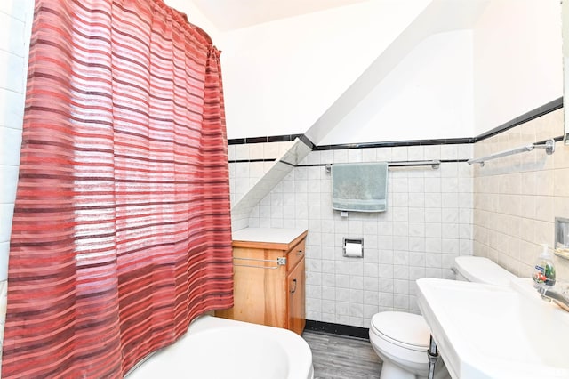 bathroom featuring a shower with shower curtain, a sink, tile walls, and toilet