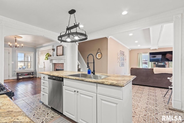 kitchen featuring a sink, open floor plan, arched walkways, white cabinets, and dishwasher