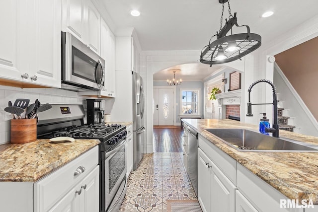 kitchen with arched walkways, a sink, decorative backsplash, appliances with stainless steel finishes, and crown molding