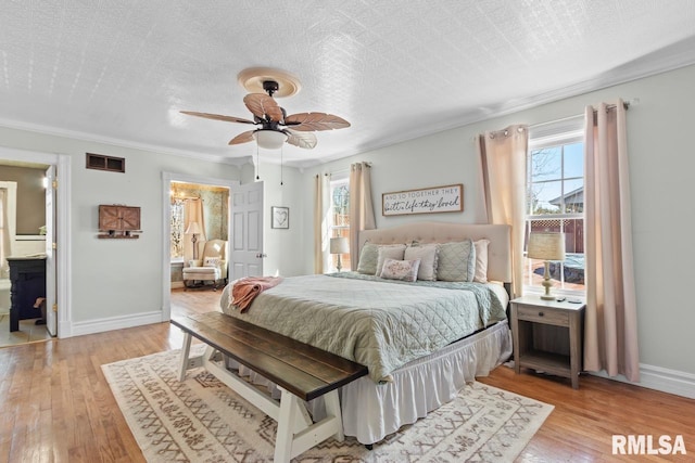 bedroom with visible vents, baseboards, a textured ceiling, and light wood finished floors