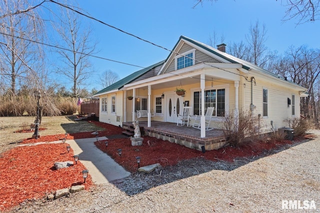 view of front facade with central air condition unit, covered porch, and a chimney