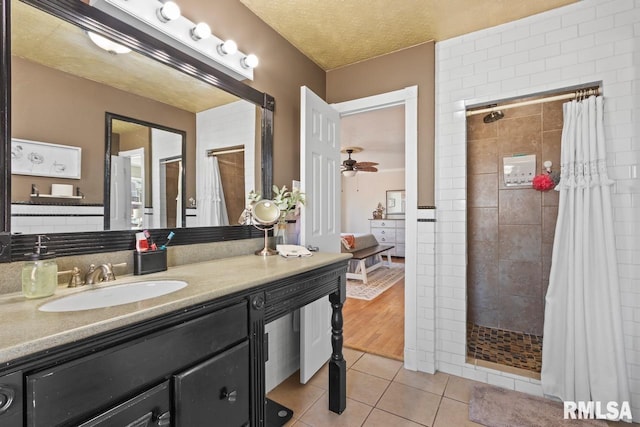 full bath with ceiling fan, a tile shower, tile patterned floors, a textured ceiling, and vanity