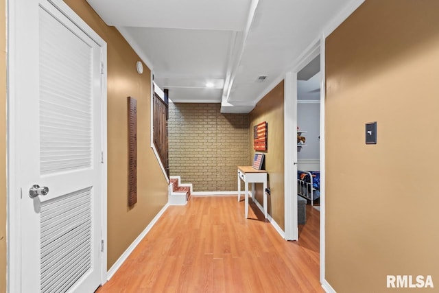 corridor with stairway, light wood-style flooring, baseboards, and brick wall