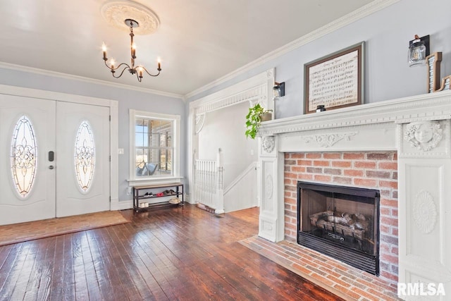 foyer entrance featuring crown molding, a chandelier, hardwood / wood-style floors, a fireplace, and french doors