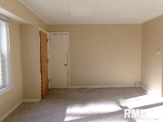 unfurnished room with baseboards and light colored carpet