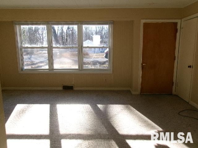 spare room featuring a healthy amount of sunlight, carpet floors, baseboards, and visible vents