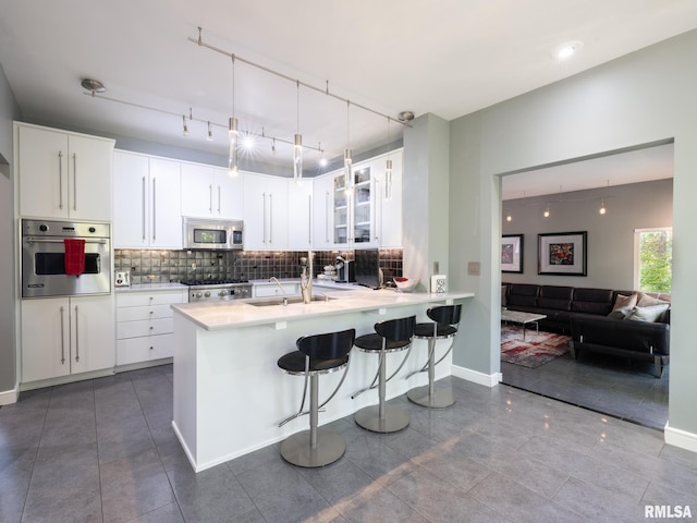 kitchen with a breakfast bar, tasteful backsplash, appliances with stainless steel finishes, glass insert cabinets, and a sink