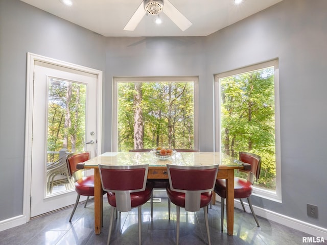 dining room featuring ceiling fan, a healthy amount of sunlight, and baseboards