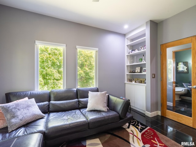 living area featuring built in shelves, recessed lighting, granite finish floor, and baseboards