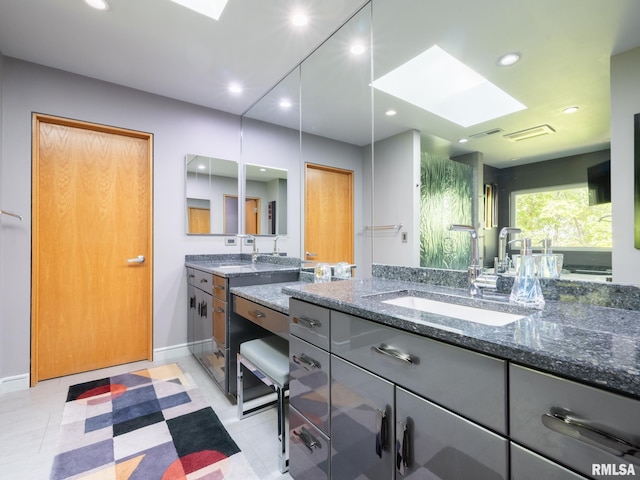 full bathroom with baseboards, a skylight, vanity, and recessed lighting