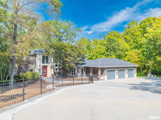 view of front of property featuring a garage, driveway, and a fenced front yard