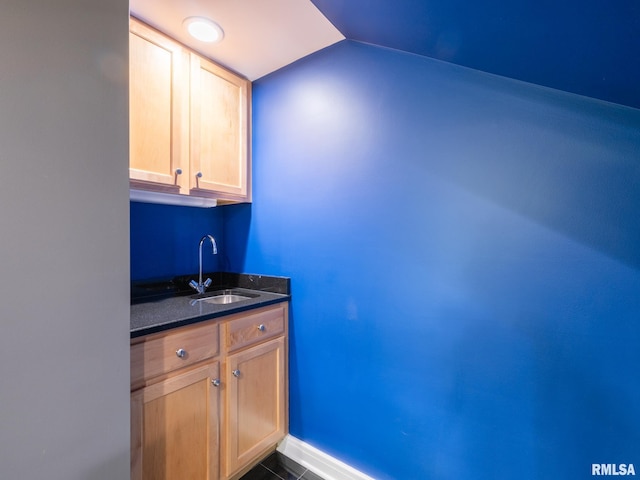 bar with vaulted ceiling, a sink, and baseboards