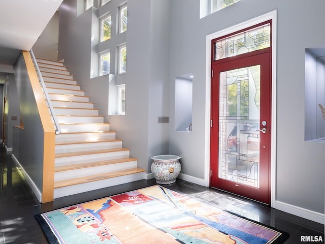 entryway with a towering ceiling, stairway, and baseboards