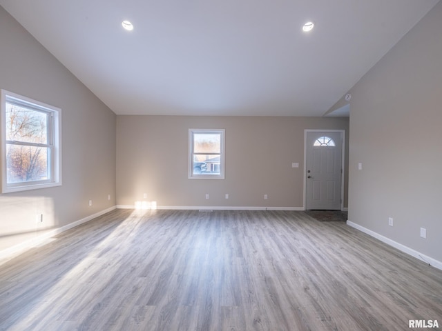 unfurnished living room with lofted ceiling, baseboards, and wood finished floors