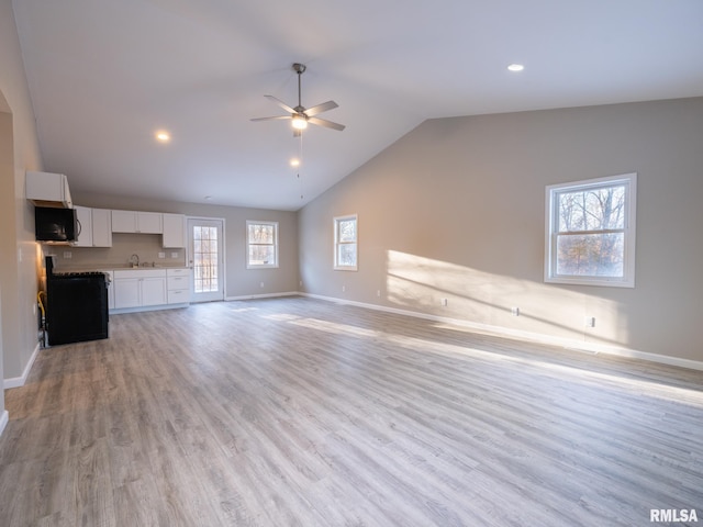 unfurnished living room with light wood-type flooring, ceiling fan, baseboards, and a sink