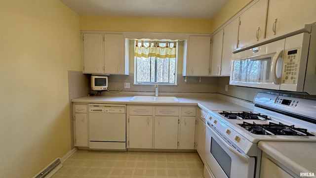 kitchen featuring light countertops, visible vents, a sink, white appliances, and baseboards