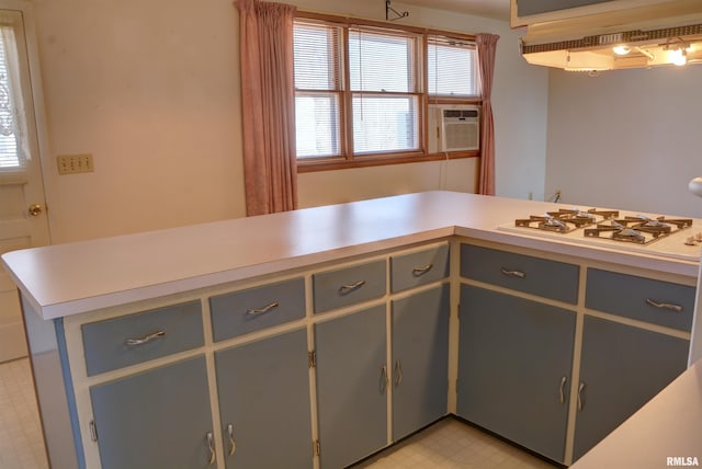 kitchen featuring light floors, light countertops, gray cabinetry, white gas cooktop, and under cabinet range hood