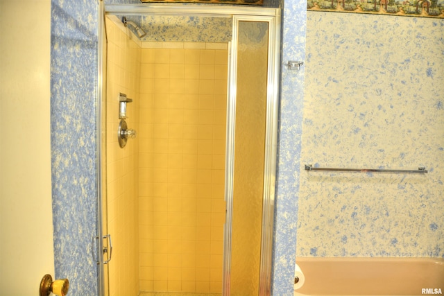 bathroom featuring a shower stall and wallpapered walls