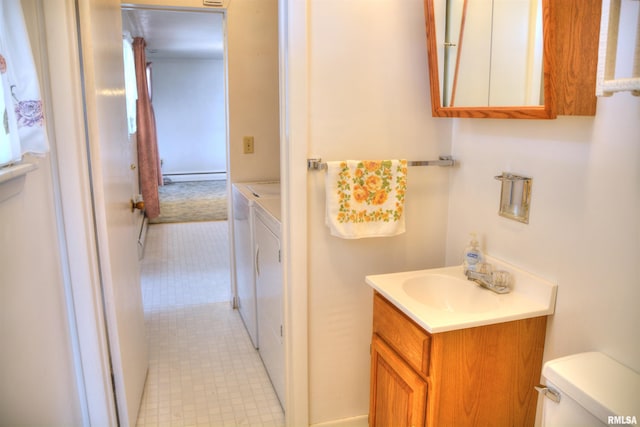 half bath with washer and clothes dryer, baseboard heating, vanity, and toilet