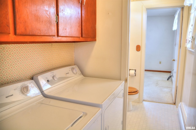 clothes washing area with baseboards, a baseboard radiator, cabinet space, and washer and dryer