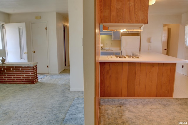 kitchen with carpet floors, white appliances, a peninsula, a sink, and light countertops