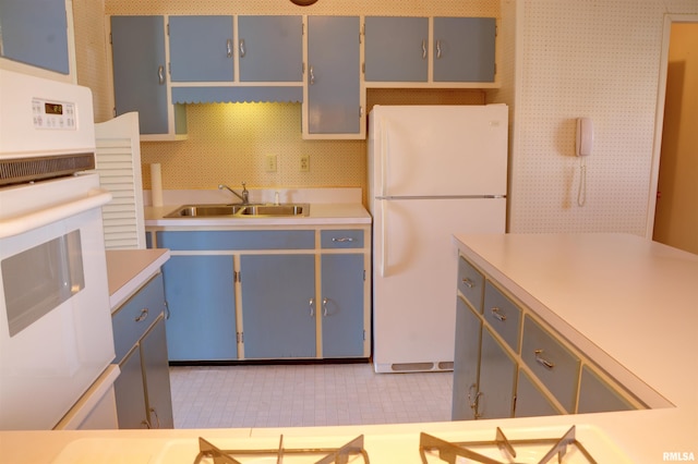 kitchen with blue cabinetry, light countertops, backsplash, a sink, and white appliances