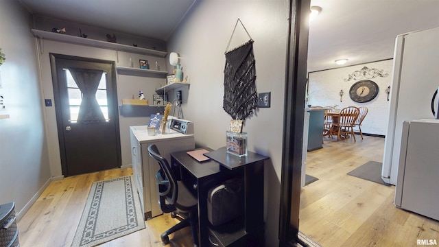 clothes washing area with light wood finished floors, baseboards, laundry area, and washer and dryer