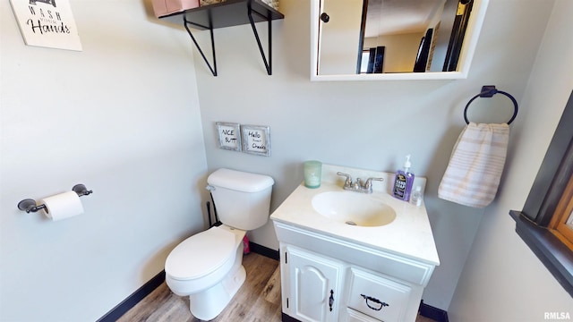 bathroom featuring baseboards, vanity, toilet, and wood finished floors