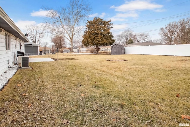 view of yard with central air condition unit, a storage shed, a fenced backyard, and an outbuilding