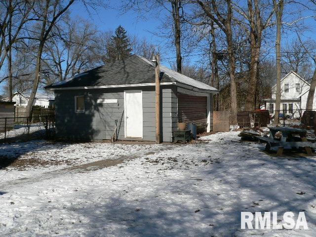 snow covered garage with a detached garage and fence