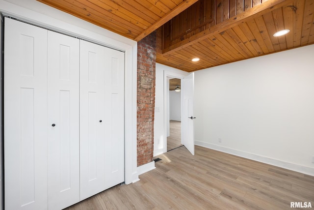 unfurnished bedroom with wooden ceiling, brick wall, baseboards, light wood-style floors, and a closet