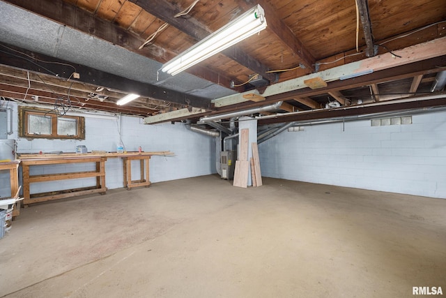 unfinished basement featuring concrete block wall and heating unit