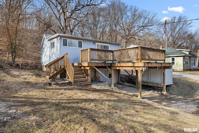 back of property with dirt driveway, stairway, and a deck