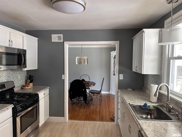 kitchen featuring light wood finished floors, stainless steel appliances, visible vents, white cabinets, and a sink