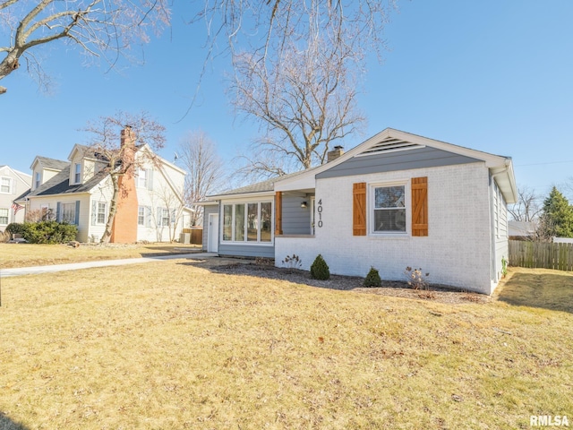 view of front of house with brick siding, a front lawn, and fence