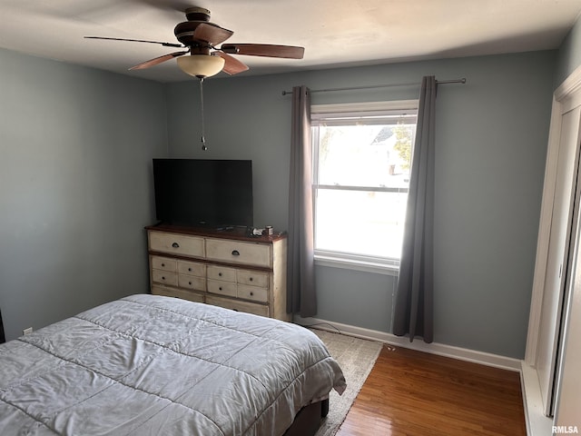 bedroom with a ceiling fan, baseboards, and wood finished floors