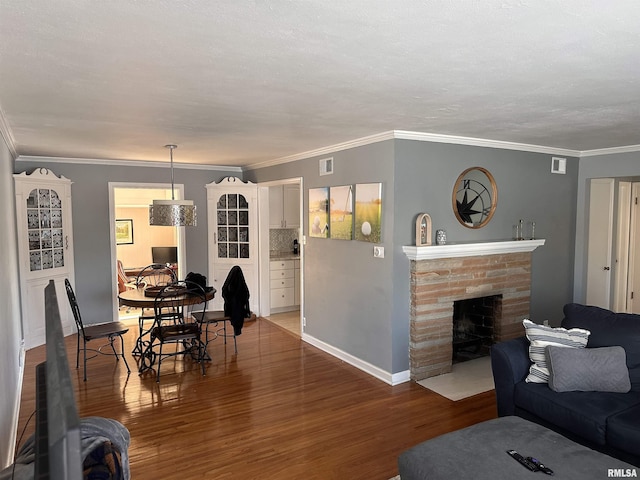 living area with a fireplace with flush hearth, ornamental molding, wood finished floors, and baseboards