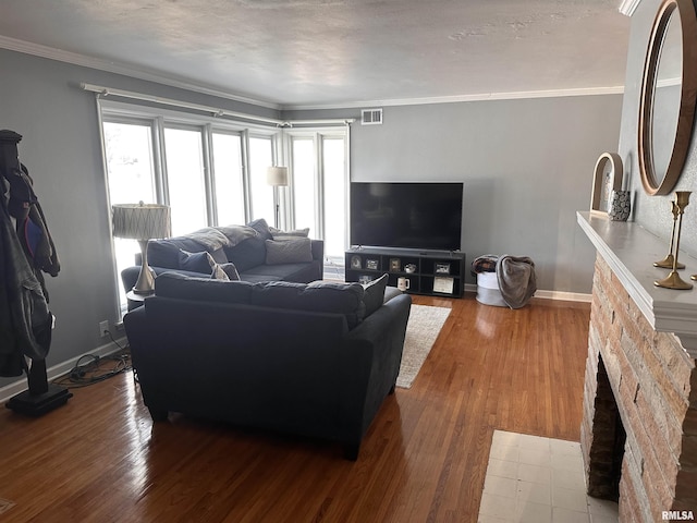 living area with baseboards, wood finished floors, visible vents, and crown molding