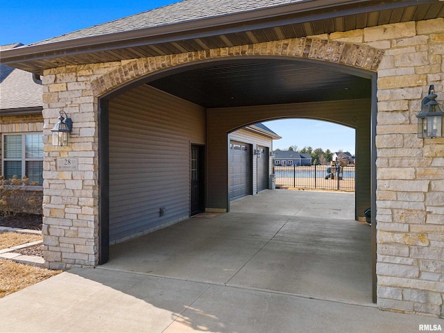 exterior space with fence, a shingled roof, stone siding, and a garage