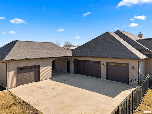 view of front of house with fence, concrete driveway, roof with shingles, and a garage