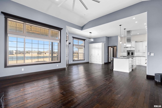 unfurnished living room featuring vaulted ceiling, ceiling fan, baseboards, and dark wood-style flooring