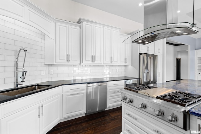 kitchen with dark countertops, tasteful backsplash, a sink, island exhaust hood, and stainless steel appliances