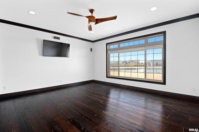 spare room featuring dark wood-type flooring, a ceiling fan, baseboards, and ornamental molding