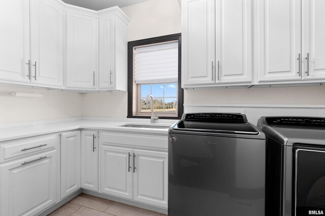 clothes washing area with cabinet space, washing machine and clothes dryer, light tile patterned floors, and a sink