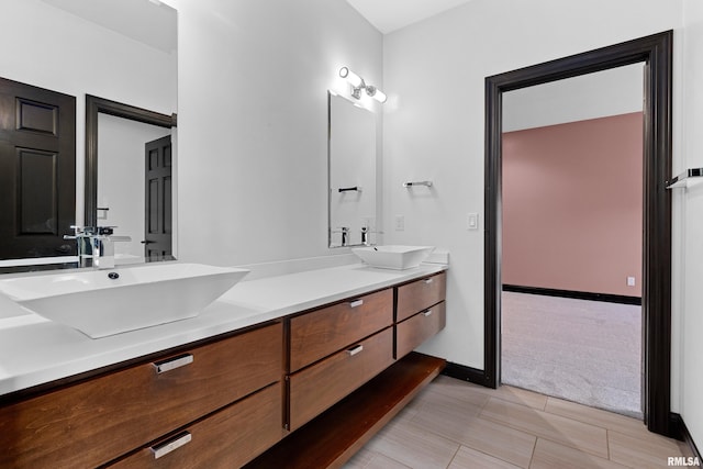 full bath featuring tile patterned floors, baseboards, a sink, and double vanity