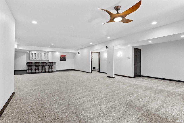 finished below grade area featuring a community bar, baseboards, carpet floors, and recessed lighting