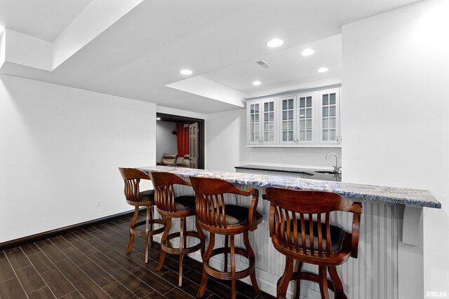 bar featuring a sink, indoor wet bar, baseboards, dark wood-style flooring, and recessed lighting