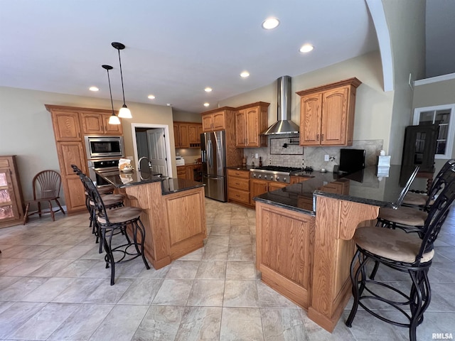 kitchen with a breakfast bar area, backsplash, appliances with stainless steel finishes, wall chimney range hood, and a peninsula