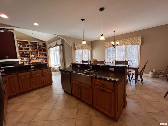 kitchen with brown cabinets, vaulted ceiling, a sink, an island with sink, and dishwashing machine