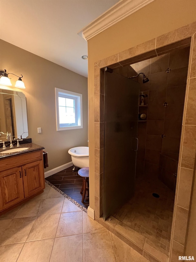 full bathroom with a freestanding bath, a stall shower, vanity, baseboards, and tile patterned floors